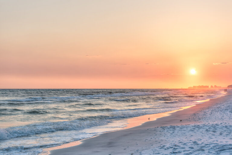 Dreamy pink peach orange sunset in Santa Rosa Beach, Florida with Pensacola coastline coast cityscape skyline in panhandle with ocean gulf mexico waves, birds