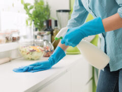 Woman cleaning and polishing the kitchen worktop with a spray detergent, housekeeping and hygiene concept